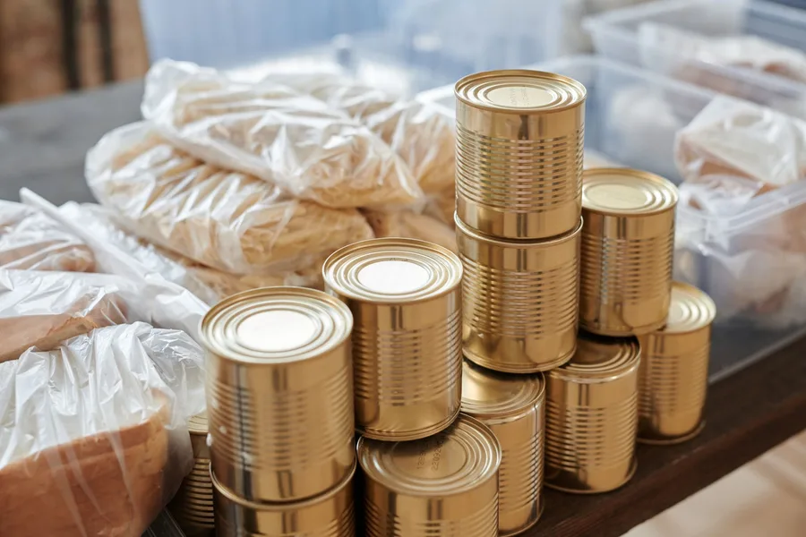 Stacked canned goods and packaged bread on a table at a distribution site