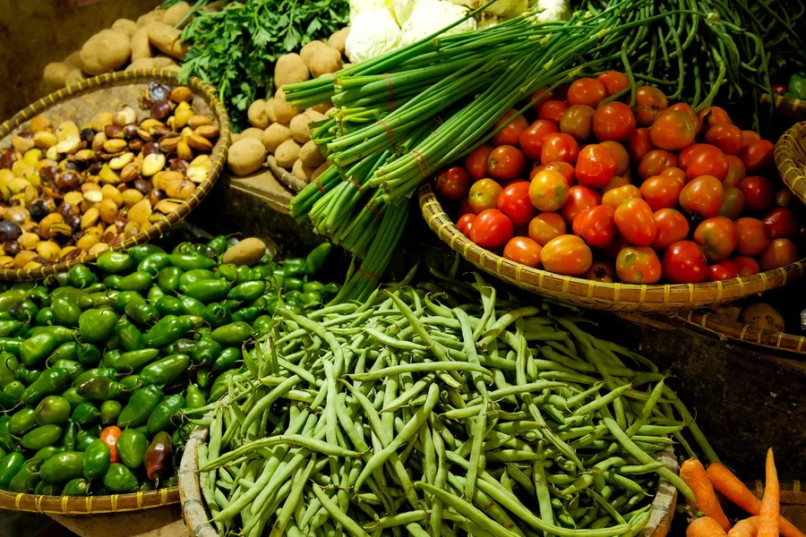 Fresh vegetables in market baskets — green beans, tomatoes, peppers, potatoes and carrots
