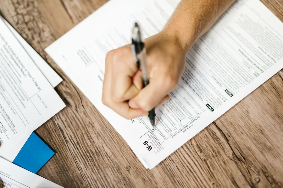 Close-up of a person filling out a printed form with a pen