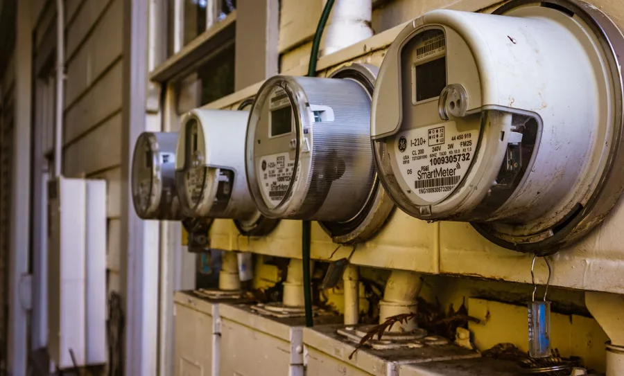 A row of residential electric meters mounted outside a multi-unit building