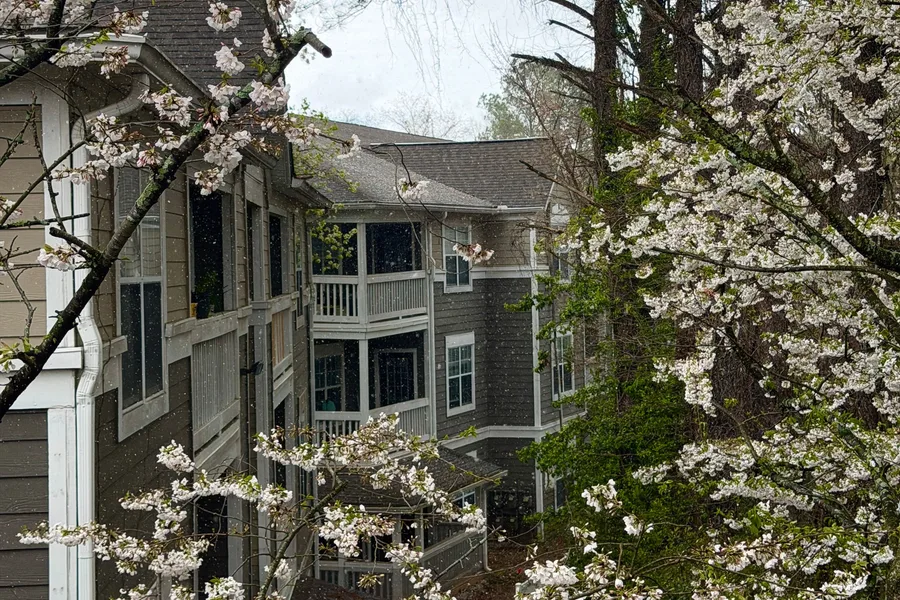 A three-story garden apartment building among flowering trees