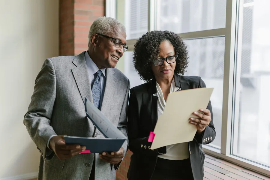 An older man and a program staff member reviewing paperwork in a folder together