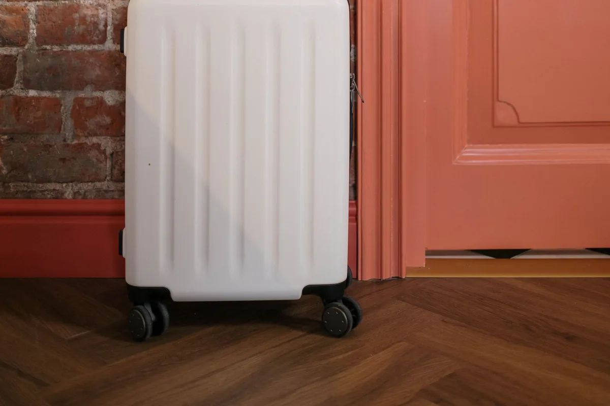 A packed carry-on suitcase standing by an open door in a hallway
