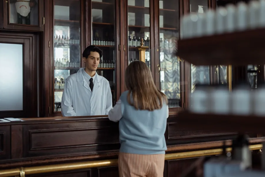 A customer talks with a pharmacist across a pharmacy counter
