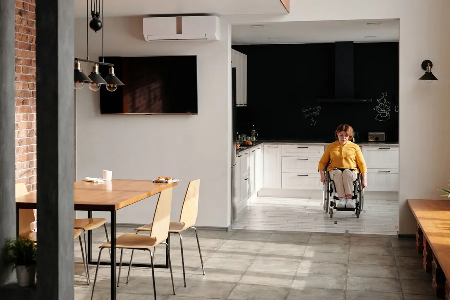 A woman using a wheelchair moving freely across the open floor of her own kitchen