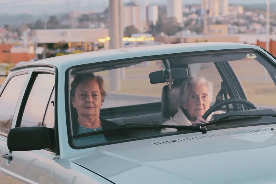 Two older women in a car, one at the wheel, heading out for the day