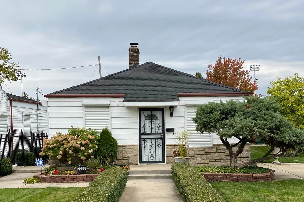 A modest single-story house with a well-kept front walk and mailbox on an overcast autumn day