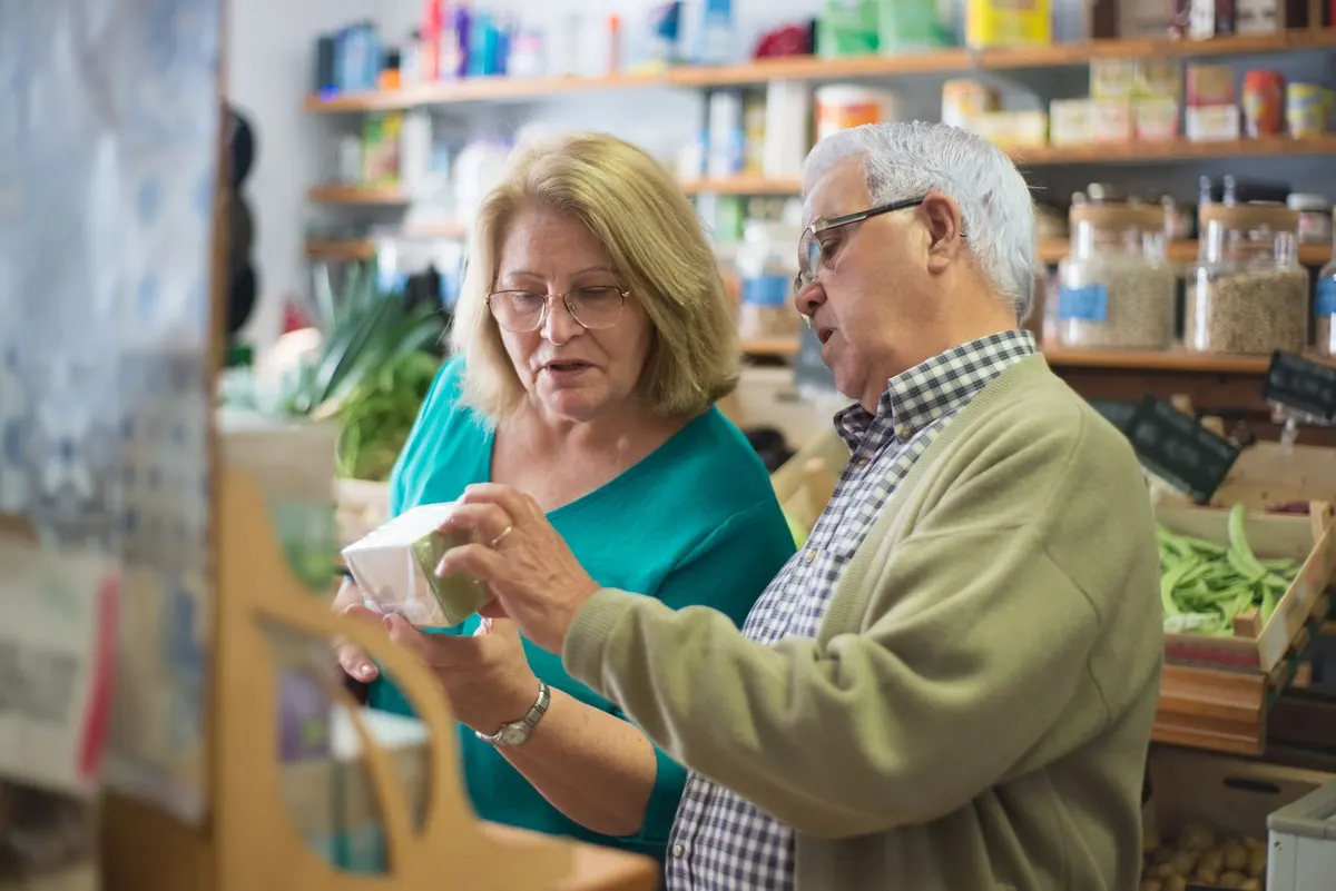 An older couple reading a product label together while shopping for groceries