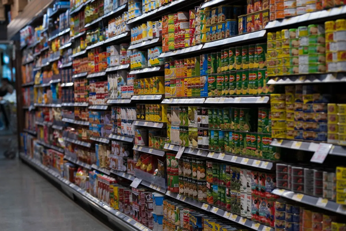 A long supermarket aisle stocked from floor to ceiling with canned and packaged food